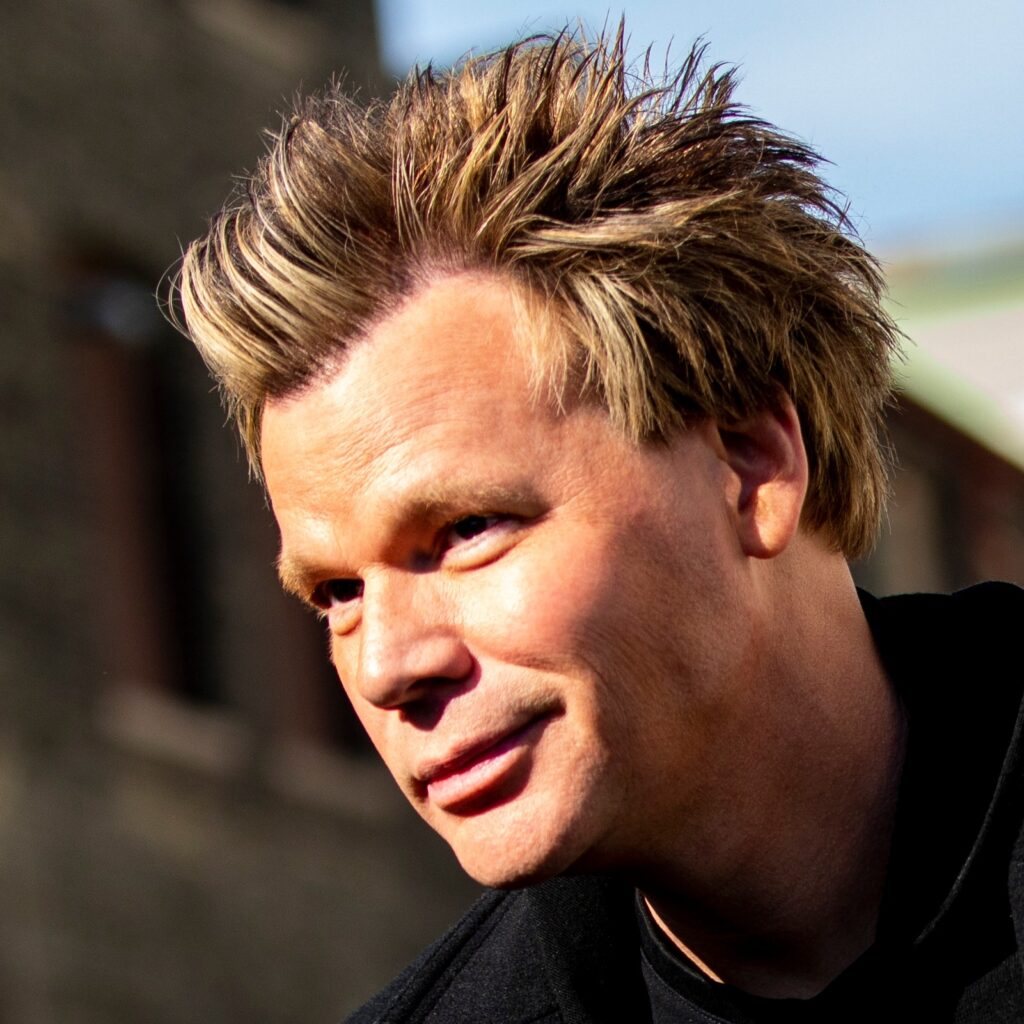 Portrait of a man with spiky blond hair in natural light.